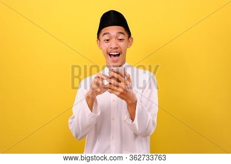 Happy Excited Young Asian Muslim Man Wearing Moslim Clothes Holding Mobile Phone Look At Phone Scree