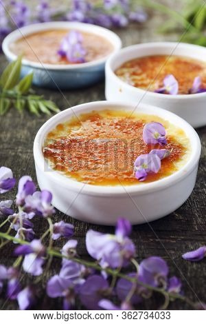 Creme Brulee, French Traditional Dessert, Three Portions, Flowering Purple Wisteria Dressing. Rustic