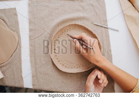 Woman Hands Laying In A Pattern On A Soft Unfired Clay Plate