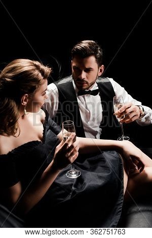 Elegant Man And Woman Holding Champagne Glasses And Looking At Each Other While Sitting Isolated On 