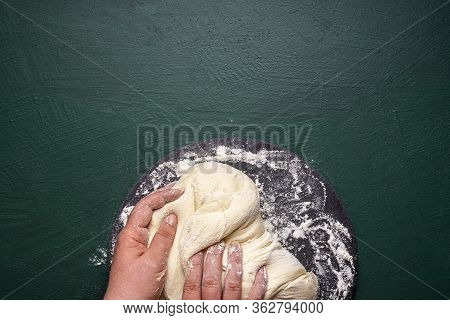 Preparing Pizza Dough On A Floured Platter, On A Green Table. Top View Of Woman Hands Kneading Dough