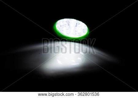 Green Led Torch Shining A Light On A White Surface In A Darkened Room