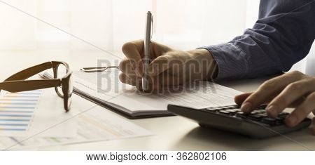 Young Woman Using Calculator, Calculating Finance At Workplace, Female Hands And Paper Document At T