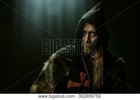 Portrait of a medieval pilgrim in old historical clothes over black background. Historical reenactment. Copy space.