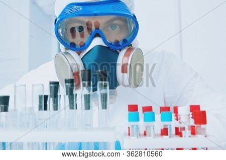 COVID-19. Doctor, microbiologist, scientist in a protective suit, makes a research on blood samples of infected people in the laboratory. Coronavirus test.