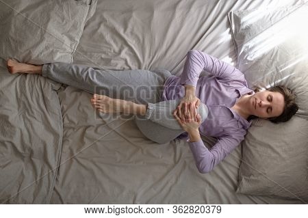 Woman Lying On Bed In The Morning And Doing Stretching Exercise From Yoga