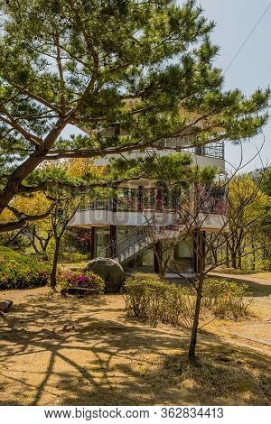 Three Story Pavilion Behind Evergreen Tree In Rural Public Park.
