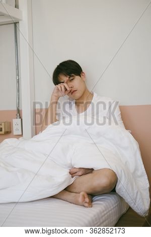 A Dozy Guy Sit On The Bed Because He Don't Want To Wake Up In His Day Off.