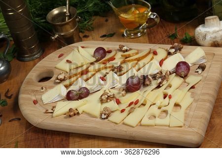 Wooden Plateau With Fresh Grapes Figs And Types Of Cheese Closeup As Homefood Background
