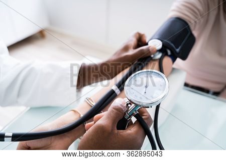 Close-up Of Doctor Measuring Patients Blood Pressure With Stethoscope