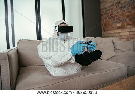 Kyiv, Ukraine - April 11, 2020: Man In Hazmat Suit, Medical Mask, Latex Gloves And Virtual Reality H