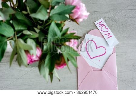 Bouquet Of Pink Peonies In Glass Vase Against White Background And Wooden Table. Mothers Day Card. B