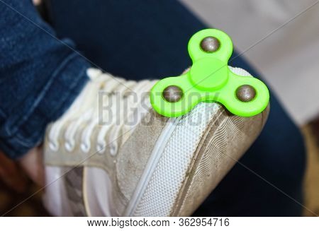 Green Spinner On The Foot Shod In Sneakers.
