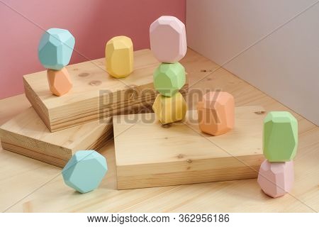 Abstract Figures From Elements Of Wooden Tumi Ishi Pastel Colors On A Wooden Podium On A Paper Backg