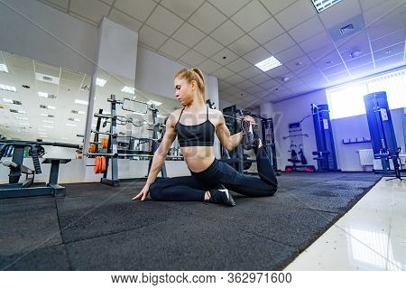 Side View Of Attractive Sportswoman Doing Exercises On The Floor Near Modern Simulators In The Fitne