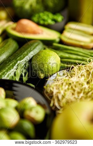 Green healthy food composition with avocado, broccoli, apple smoothie cucomber asparagus kiwi bean. Placed on dark background. Top view.