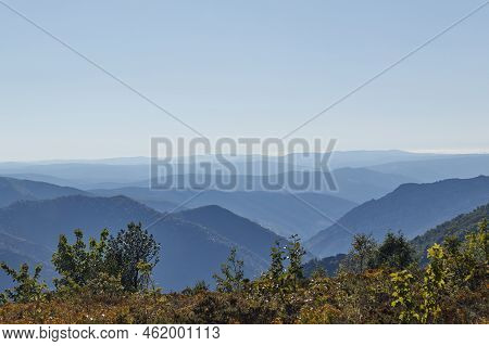 Mountain Peaks Flee To The Horizon Similar To Waves In The Sea Under A Blue Sky And Vegetation In Th