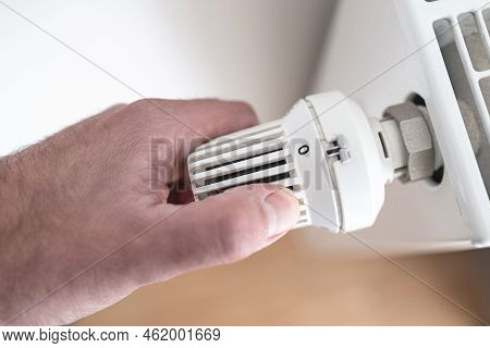 Close-up View Of Person Turning Down Thermostat On Radiator To Zero To Save Energy And Money, Rising