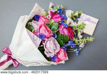 Close Up Of Bouquet Of Roses Foxgloves Bachelor Buttons Flowers Wrapped In Paper With Gift Box. Pres