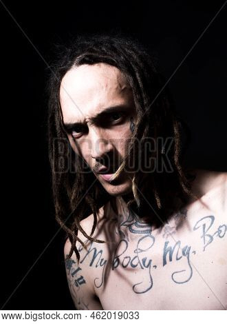 Confident Attractive Man With Serious Face. Tattooed Hipster On Black Studio.