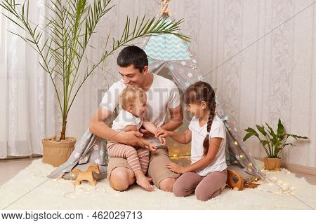 Indoor Shot Of Attractive Father And His Little Daughters Having Fun And Playing In Peetee Tent In C