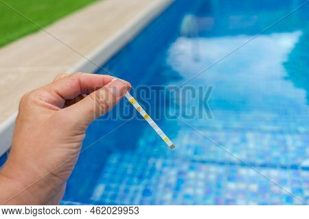 Hand With Measuring Pool Strips To Check Water Quality In A Swimming Pool
