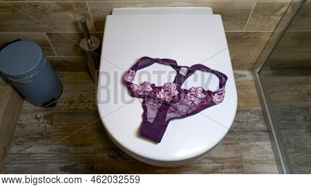 Pink Lace Women's Panties With Flowers Lie On The Toilet. Luxurious Elegant Sexy Women's Thong Lies
