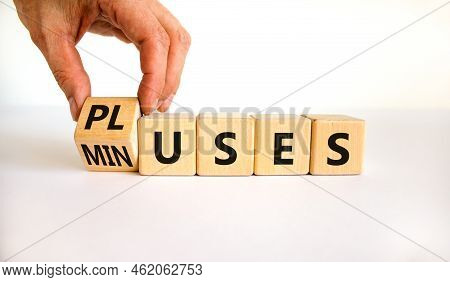Pluses And Minuses Symbol. Businessman Turns A Wooden Cube And Changes The Word 'minuses' To 'pluses