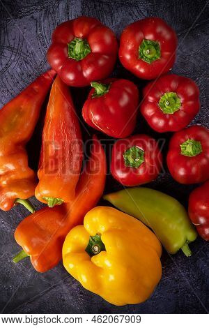 Top View Of A Bunch Of Colorful Sweet Peppers On A Dark Blue Background. Shades Of Flowers, A Set Of