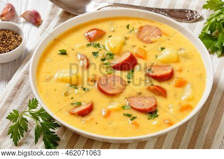 Kartoffelsuppe, German Potato Soup With Sausages In White Bowl On White Wooden Table, Landscape View