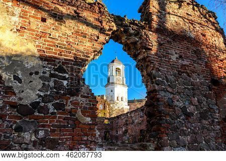 Tower Framed By A Broken Wall Opening. House Windows. Clock Tower In Vyborg, Former Bell Tower Of Th
