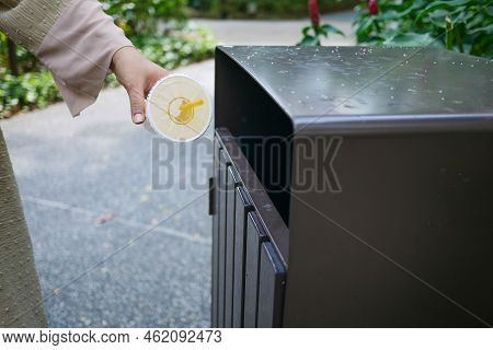 Women Hand Throwing An Empty Plastic Water Bottle In The Garbage Trash Or Bin