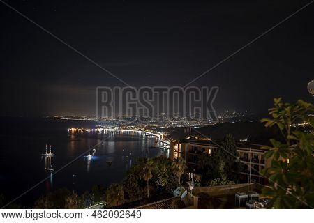 Idyllic View Of Hotel Elios And Mount Etna At Illuminated Coast By Sea In Night