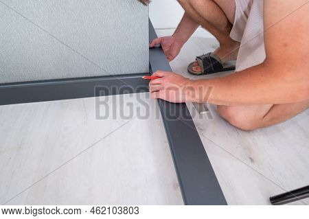 The Master Measures The Length Of The Plinth For Cutting, Installing The Plinth On The Corner Of The