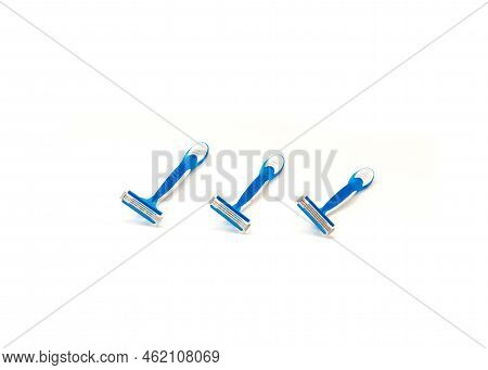 Three Brand New Blue And White Plastic Disposable Razors With Ergonomic Handle Isolated On White Bac