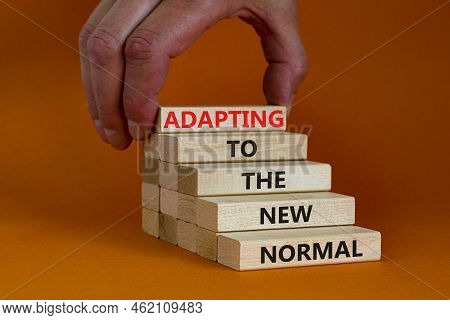 Adapting To The New Normal Symbol. Wooden Blocks With Words Adapting To The New Normal On Orange Bac
