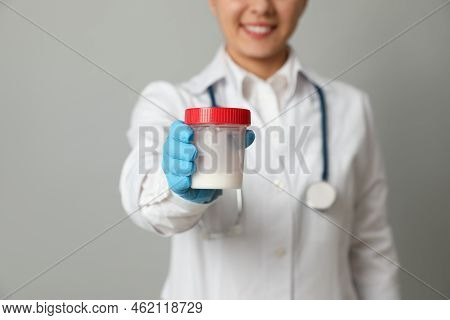 Doctor Holding Container With Sperm On Grey Background, Closeup
