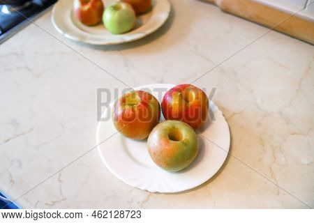 Closeup Of The Three Ripe Red And Yellow Apples With Removed Core On The White Plate