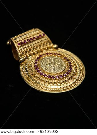 Gold Pendant Decorated With Precious Stones Isolated In A Black Background