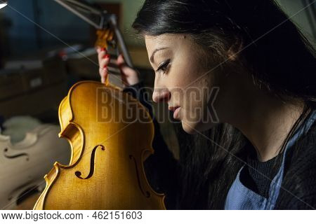 Young Woman Apprentice Violinmaker Checking Her Violin