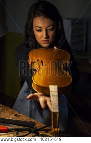 Young Woman Apprentice Violinmaker Checking Her Violin