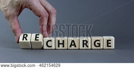 Charge Or Recharge Symbol. Businessman Turns Wooden Cubes And Changes The Word 'charge' To 'recharge