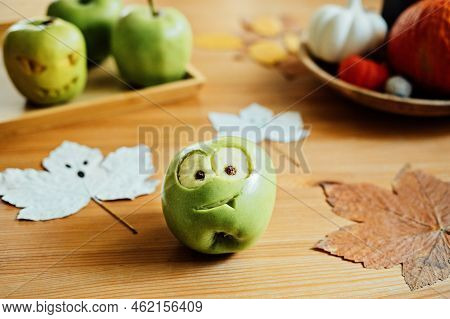 Halloween Fruit Ideas. Halloween Green Apple With Creepy Carved Face On Wooden Table At Home. Health