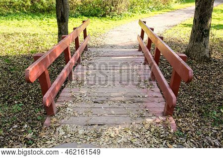 Small Wooden Brodge With Red Railings In A Park In Sunny Day