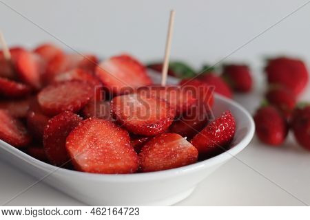 Half Cut Fresh Strawberries With Sugar Springled On Top Inside A White Bowl, Shot On White Backgroun