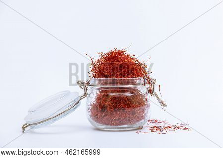 Glass Jar Filled With Red Saffron Stamens On A White Background. Expensive Spice.