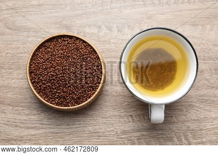 Buckwheat Tea In Cup And Bowl With Granules On Wooden Table, Flat Lay