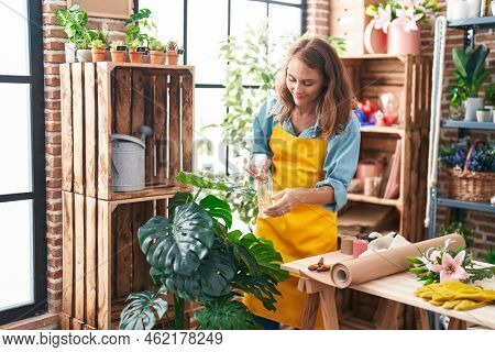 Young beautiful hispanic woman florist using difusser working at florist