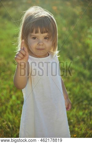 Charming Child In Linen Dress Walking On The Lawn