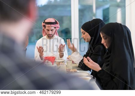 Muslim family making iftar dua to break fasting during Ramadan.